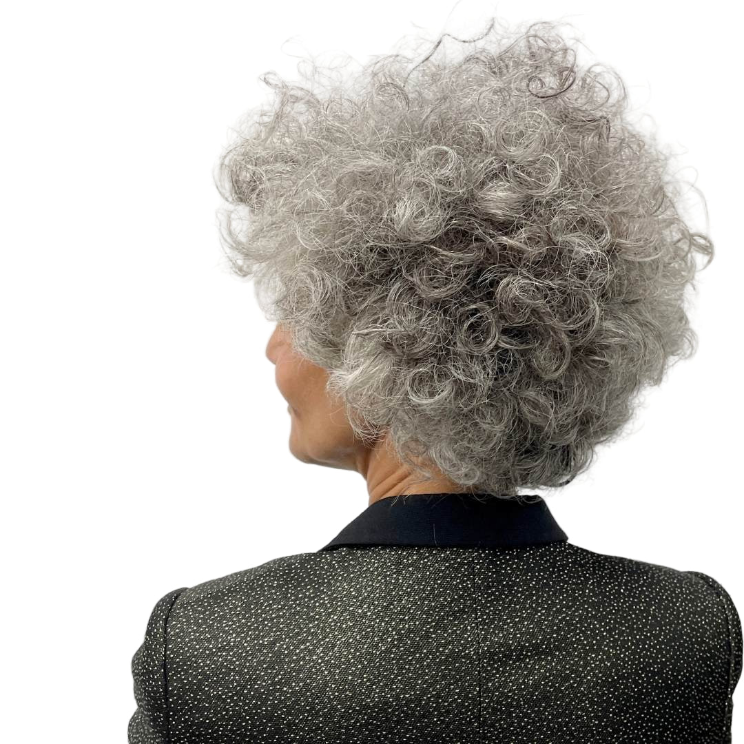 Person with gray curly hair wearing a black jacket against a light background
