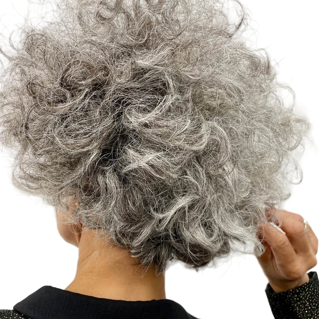Close-up of a person with gray, curly hair against a plain background