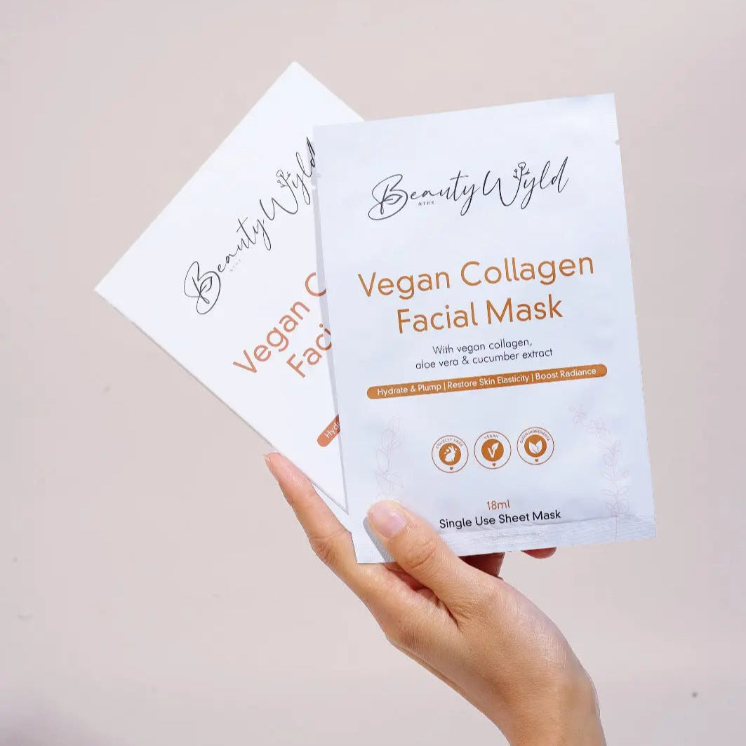 Hand holding two Beauty Wyld Vegan Collagen Facial Mask packages against a beige background