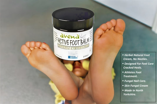 Natural peppermint foot balm held between bare feet for tired foot relief