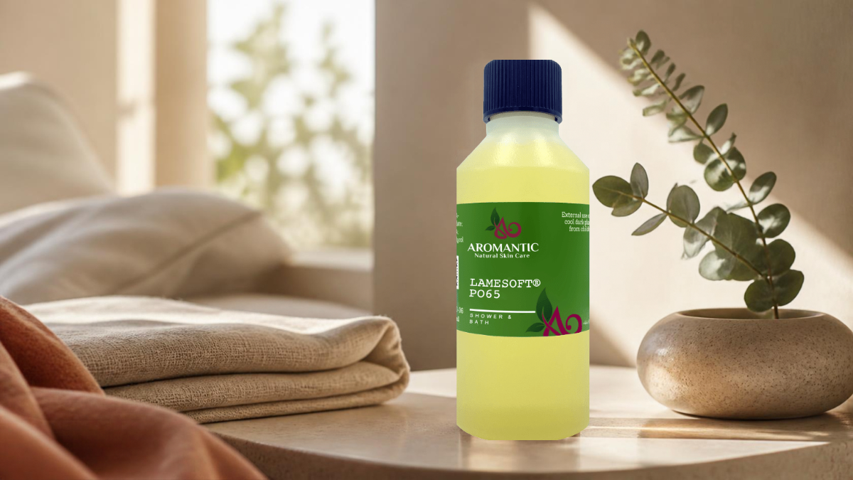 A bottle of Aromantic Lamesoft Moss hair oil with a green label and blue cap, set on a wooden table next to a folded blanket and a small potted eucalyptus branch in a warm, softly lit room.